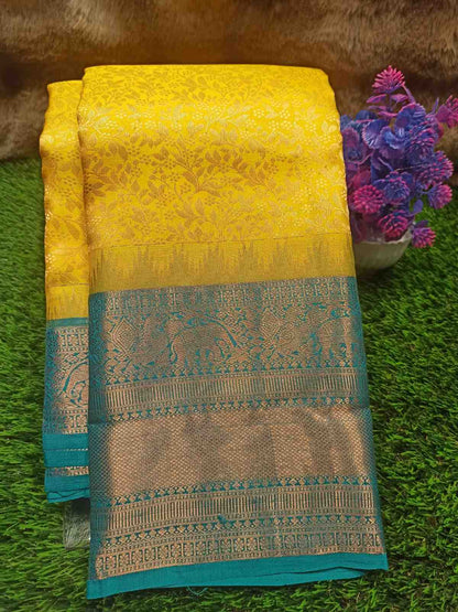 Yellow and blue saree with intricate patterns on a green surface