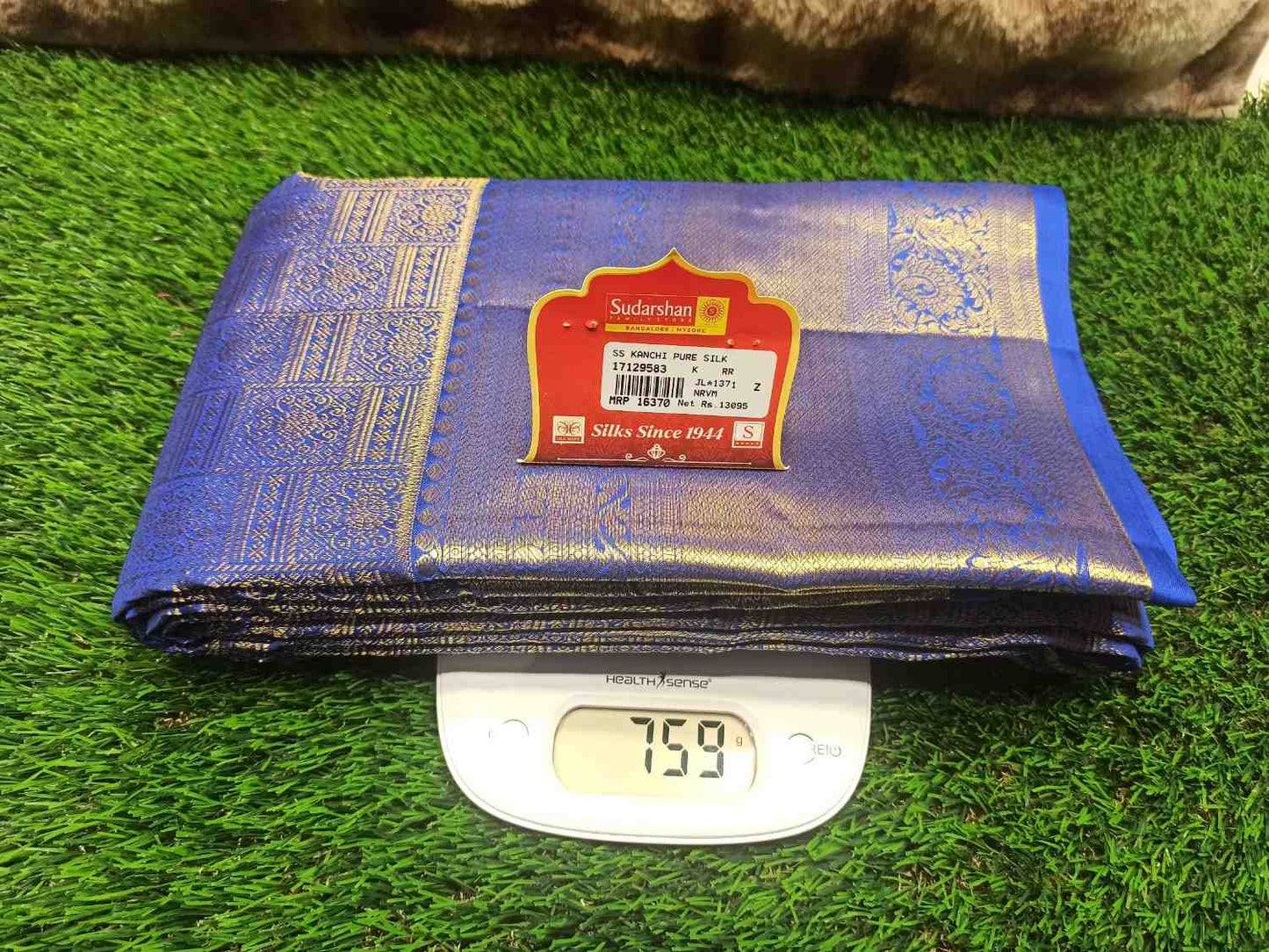 Blue fabric with a brand label on a digital scale against a green grass background