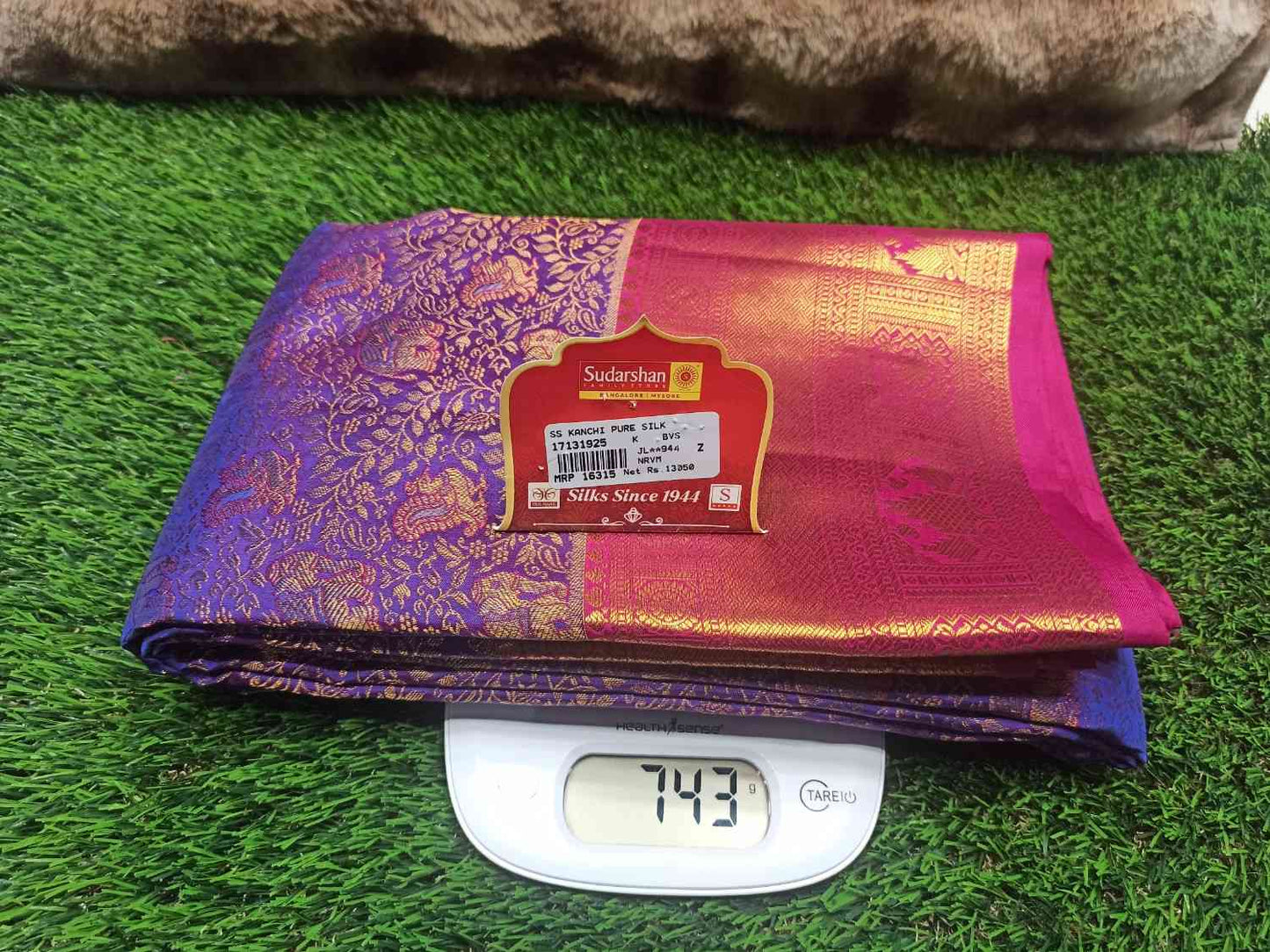 Purple and pink saree with a brand label on a digital weight scale